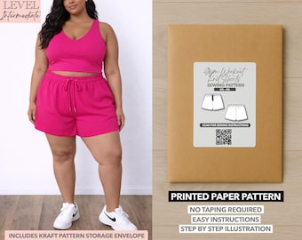 Può includere: Una donna indossa un completo da allenamento magenta, composto da un crop top e pantaloncini. L'immagine mostra anche una busta di carta marrone con il modello "Gym Workout Knit Shorts Sewing Pattern". Il modello include un codice QR e il testo "Printed Paper Pattern".