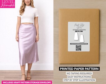 Può includere: Una donna indossa un top bianco e una gonna midi lilla. Viene mostrata anche una busta di carta modello marrone con un'etichetta bianca che recita "Midi Slip Skirt Sewing Pattern". La busta include il testo "Printed Paper Pattern".