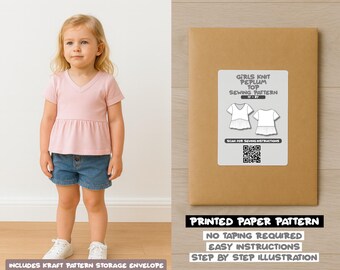 Op de afbeelding: Een jong meisje draagt een roze peplum top en een spijkerbroek short, naast een bruine papieren patroon envelop. De envelop heeft een label met de tekst "GIRLS KNIT PEPLUM TOP SEWING PATTERN". De tekst "PRINTED PAPER PATTERN" is ook zichtbaar.