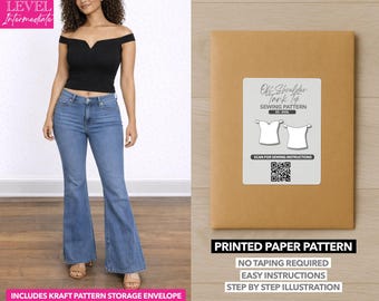 Può includere: Una donna indossa un top nero con spalle scoperte e jeans blu. Una busta di carta marrone con un'etichetta bianca che recita "Off Shoulder Tank Top Sewing Pattern". Il testo "Printed Paper Pattern" è sotto l'etichetta.
