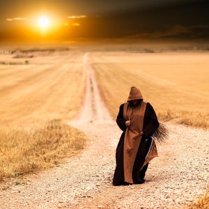 May include: A person wearing a brown hooded robe walks down a dirt road in a field of dry grass. The sun is setting in the background.