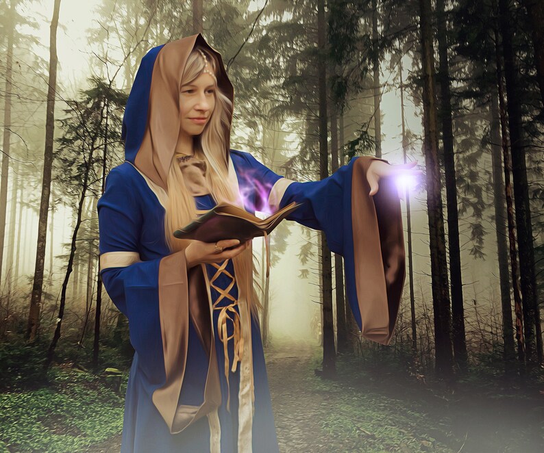 May include: A woman wearing a blue and brown hooded robe casts a spell with a book in a misty forest setting.