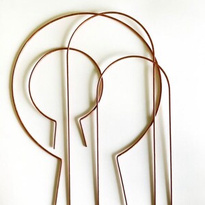 May include: Set of four copper wire plant hoops, each with a different size. The hoops are curved and have a rounded top. They are perfect for supporting climbing plants.