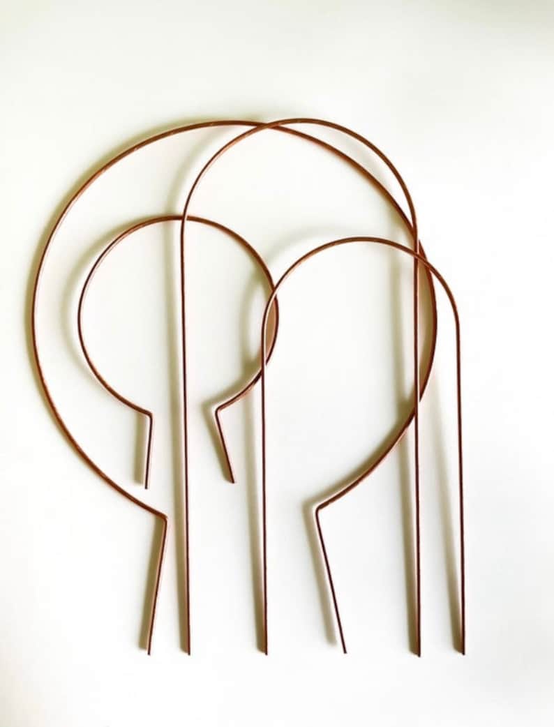 May include: Set of four copper wire plant hoops, each with a different size. The hoops are curved and have a rounded top. They are perfect for supporting climbing plants.