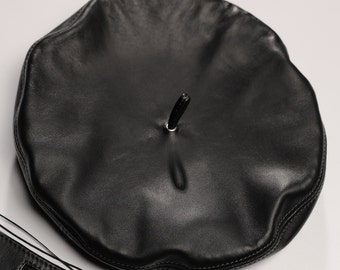May include: A black leather beret with a small black loop on top.