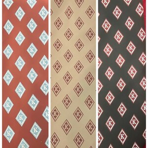 May include: Three neckties with repeating diamond patterns. The first tie is a reddish-brown color with light blue diamonds containing the letter "K". The second tie is tan with maroon diamonds. The third tie is dark gray with red diamonds.
