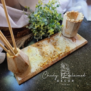 May include: A rectangular resin tray with a marbled white and gold finish, featuring two matching hexagonal holders. One holder contains three wooden sticks. The tray surface has gold leaf accents. The text Chicly Reclaimed DECOR By Renee is visible.
