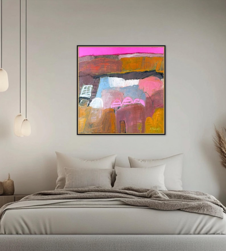 May include: Abstract landscape painting in a black frame. The artwork features a vibrant color palette with pink, orange, blue, and yellow hues. The painting is displayed above a bed with neutral-toned bedding.