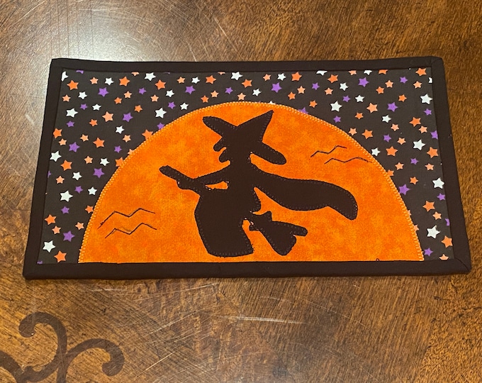 Halloween witch in front of a moon mug rug