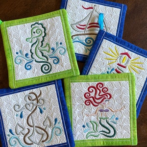 May include: Set of five green and blue quilted pot holders with embroidered nautical designs. The designs include a seahorse, a sailboat, a lighthouse, an anchor, and a mermaid.
