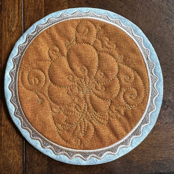 Pumpkin Pie Hot Pad Trivet.  Shaped like a pumpkin pie.  Approximately 8.5 inches.  Embroidered and quilted.