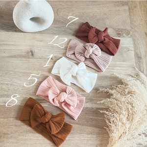 Może przedstawiać: Sześć różnych kolorowych, żebrowanych opasek do włosów z kokardką. Opaski są w odcieniach brązu, różu i bieli.