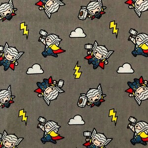 May include: A grey fabric with a repeating pattern of a cartoon character holding a hammer. The character is wearing a red cape, a blue shirt, and a yellow belt. The background is grey with white clouds and yellow lightning bolts.