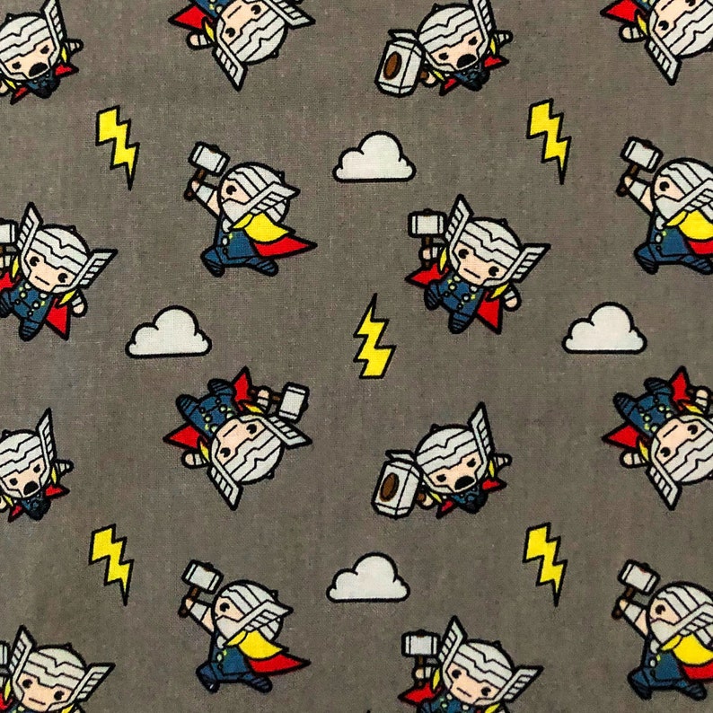 May include: A grey fabric with a repeating pattern of a cartoon character holding a hammer. The character is wearing a red cape, a blue shirt, and a yellow belt. The background is grey with white clouds and yellow lightning bolts.