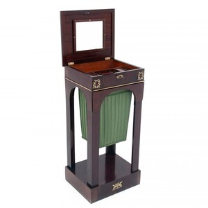 Puede incluir: Un soporte de madera oscura con un forro de tela verde y una tapa con bisagras con un espejo. El soporte tiene detalles decorativos de latón.