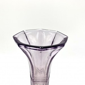 May include: A clear glass vase with a purple tint and a hexagonal opening. The vase has a flared, trumpet-shaped opening and a slender, cylindrical base.