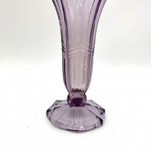 May include: A pale lavender glass vase with a fluted design and a geometric base.