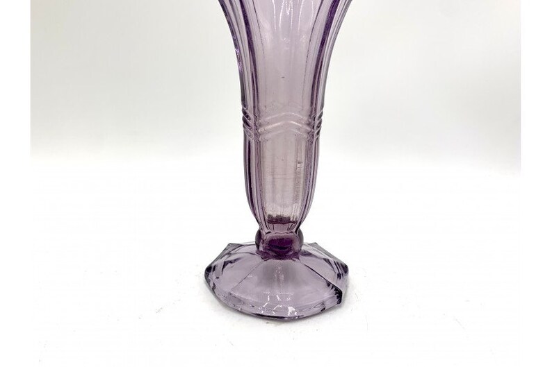 May include: A pale lavender glass vase with a fluted design and a geometric base.