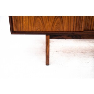 Peut inclure: Gros plan d'un buffet en bois avec une finition brun fonc&eacute;. Le buffet a un design simple avec un dessus rectangulaire et quatre pieds. Les pieds sont en bois identique &agrave; celui du buffet et sont effil&eacute;s.