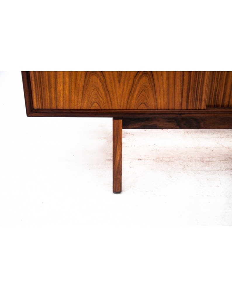 Peut inclure: Gros plan d'un buffet en bois avec une finition brun fonc&eacute;. Le buffet a un design simple avec un dessus rectangulaire et quatre pieds. Les pieds sont en bois identique &agrave; celui du buffet et sont effil&eacute;s.