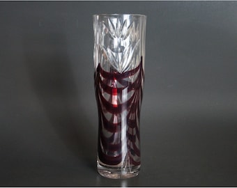 May include: A clear glass vase with a cut glass design and a dark red, almost black, geometric pattern.