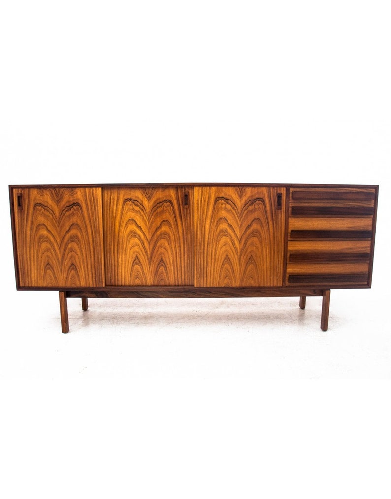 Peut inclure: Un buffet moderne du milieu du si&egrave;cle avec trois portes et quatre tiroirs. Le buffet est en bois fonc&eacute; avec un riche motif de grain. Il a un design simple avec des lignes droites et une forme rectangulaire.