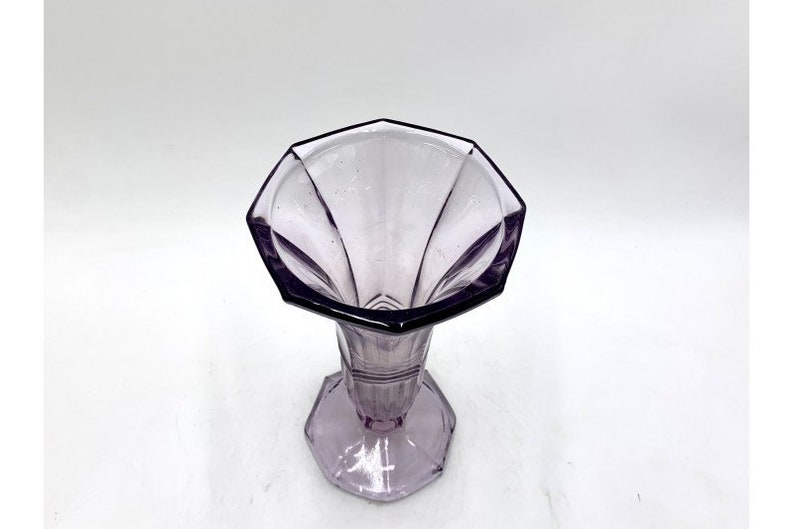 May include: A purple glass vase with a geometric design. The vase has a wide, octagonal opening and a narrow base.