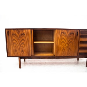 Peut inclure: Un buffet moderne du milieu du si&egrave;cle avec trois portes et une &eacute;tag&egrave;re. Le buffet est en bois fonc&eacute; avec un riche motif de grain. Les portes sont ferm&eacute;es et l'&eacute;tag&egrave;re est vide.