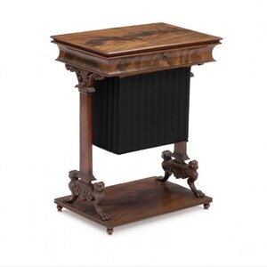 Puede incluir: Una mesa de juego de madera oscura con una tapa abatible y un cajón. La mesa tiene una base tallada con patas de garra de león.
