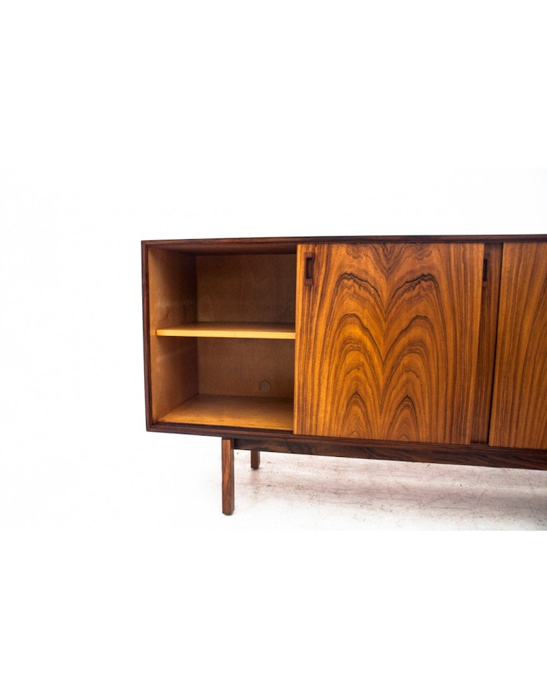 Peut inclure: Un buffet moderne du milieu du si&egrave;cle avec des portes coulissantes en bois fonc&eacute; avec un riche motif de grain. Le buffet a une seule &eacute;tag&egrave;re ouverte et repose sur quatre pieds.