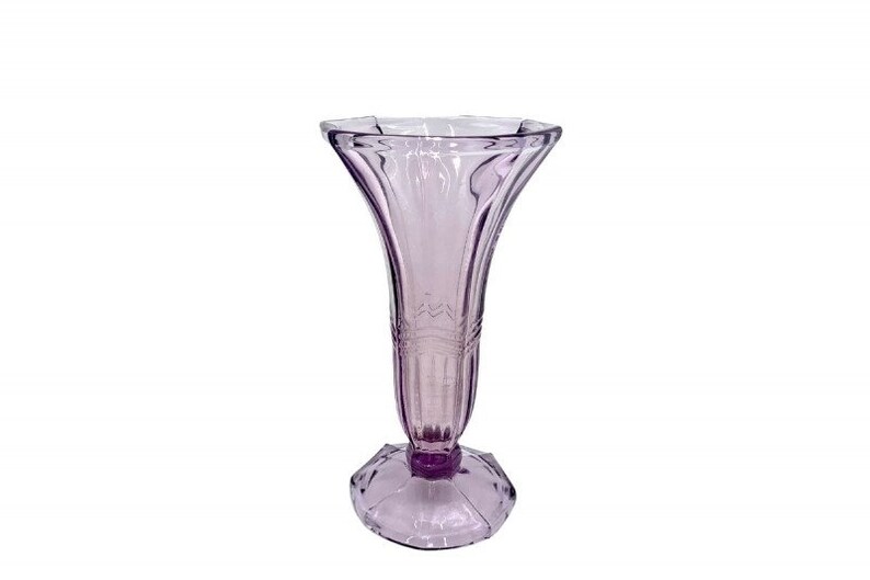 May include: A clear glass vase with a delicate, fluted design. The vase is a pale lavender color and has a wide, flared opening.