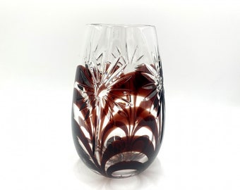 May include: A clear glass vase with a cut-glass design and a dark brown swirl pattern.