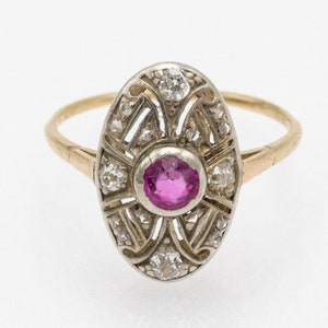 Puede incluir: Un anillo vintage con una piedra preciosa rosa rodeada de diamantes más pequeños en un delicado engaste ovalado. El anillo está hecho de oro y plata.