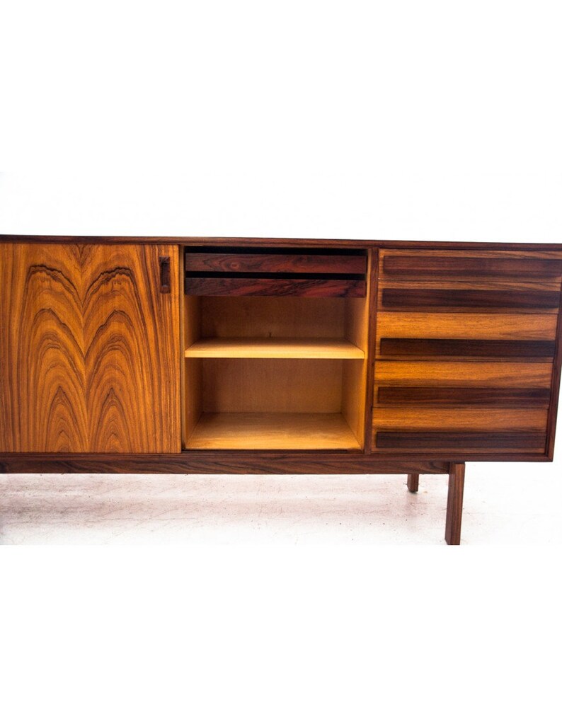 Peut inclure: Un buffet moderne du milieu du si&egrave;cle avec une finition en bois vein&eacute;. Le buffet comporte deux tiroirs, une &eacute;tag&egrave;re et une porte. La porte est ouverte, r&eacute;v&eacute;lant l'&eacute;tag&egrave;re &agrave; l'int&eacute;rieur. Le buffet est en bois et a une finition brun fonc&eacute;.