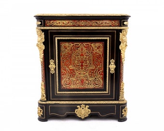 May include: A black and gold antique cabinet with intricate marquetry details and a single door. The cabinet has a decorative top and base with ornate carvings.