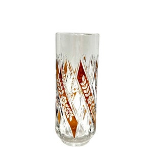 Könnte beinhalten: Ein klares Glas Trinkglas mit einem Diamantenmuster und einem braunen und weißen Blumendesign.