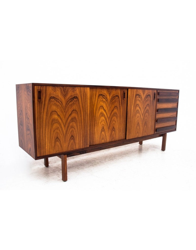 Peut inclure: Un buffet moderne du milieu du si&egrave;cle avec trois portes coulissantes et quatre tiroirs. Le buffet est en bois fonc&eacute; avec un beau grain. Il a une forme rectangulaire et repose sur quatre pieds.