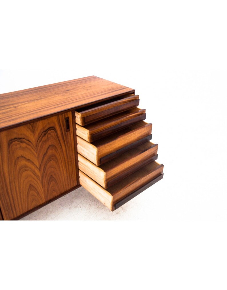Peut inclure: Un buffet moderne du milieu du si&egrave;cle avec cinq tiroirs et une porte de placard. Les tiroirs sont ouverts et faits de bois avec une finition brun fonc&eacute;. La porte du placard est ferm&eacute;e et pr&eacute;sente un motif de grain de bois.