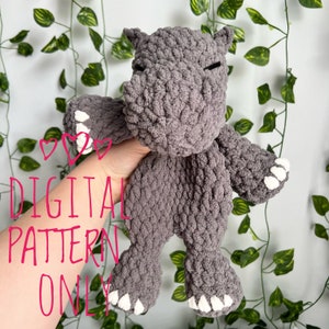 May include: A gray crocheted amigurumi hippopotamus toy with white claws. The toy is being held by a hand. The text "DIGITAL PATTERN ONLY" is visible in the image.