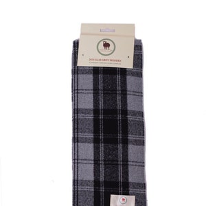 Peut inclure: Une écharpe à carreaux gris et noirs avec des franges. L'écharpe porte une étiquette indiquant "Douglas Grey Modern 2-ply soft tartan clan scarf".
