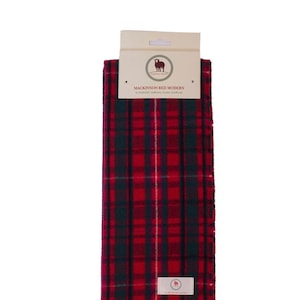 May include: A red and green tartan scarf with fringe. The scarf has a label that reads "Mackinnon Red Modern Superfine Tartan Clan Scarf".