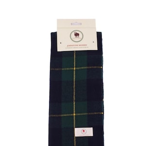 May include: A green and navy blue plaid scarf with a yellow fringe. The scarf has a label that reads "Johnstone Modern" and "Johnstone tartan (Clan Grant)".
