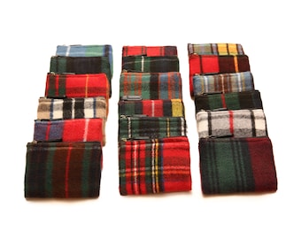 May include: A collection of rectangular plaid zippered pouches in various colors, including red, green, blue, and black. The pouches are arranged in three rows, showcasing the diverse patterns and hues of the fabric.