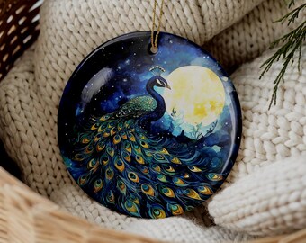 May include: A round ceramic ornament featuring a vibrant peacock with iridescent blue and green plumage. The bird is depicted against a dark, starry night sky with a large, glowing full moon. A gold string is attached to the top for hanging.