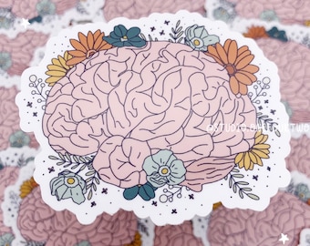 Op de afbeelding: Een roze hersenomtrek met bloemdetails in tinten geel, oranje, blauw en groen. De hersenen worden omringd door kleine witte sterren en de tekst "@studio.on.art.two" is zichtbaar in de rechterbenedenhoek.