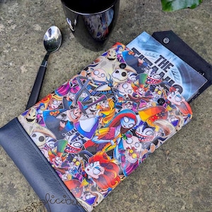May include: A colorful phone case with a Nightmare Before Christmas theme. The case features a variety of characters from the movie, including Jack Skellington, Sally, and Oogie Boogie. The case is made of a durable material and has a navy blue trim.