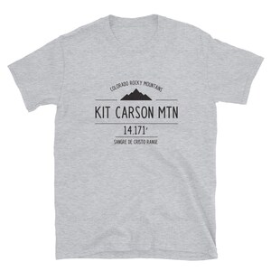 May include: Gray t-shirt with a black graphic design featuring the text "Kit Carson Mtn 14,171' Sangre de Cristo Range" and a mountain silhouette. The text "Colorado Rocky Mountains" is above the mountain silhouette.