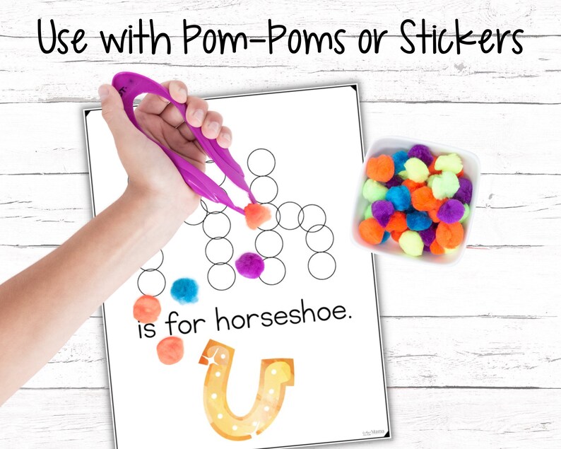 May include: A printable worksheet for learning the letter "U" with a picture of a horseshoe and the text "U is for horseshoe." The worksheet has a grid of circles for placing pom-poms or stickers. A hand is shown using tweezers to place a pink pom-pom on the worksheet. A bowl of colorful pom-poms is shown to the right of the worksheet.