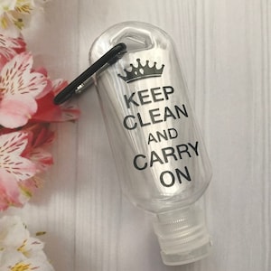May include: A clear plastic bottle with a black carabiner clip and a black and white crown graphic. The bottle has the text "Keep Clean and Carry On" printed on it.