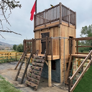 May include: A wooden playset with a two-story tower, a red flag, and climbing features. The playset includes a climbing wall, a ladder, and a rope bridge, all made of natural wood.